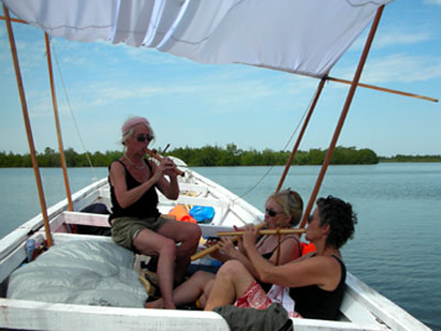 Catherine, Edie, and Vijali playing music in their pirogue, fishing canoe